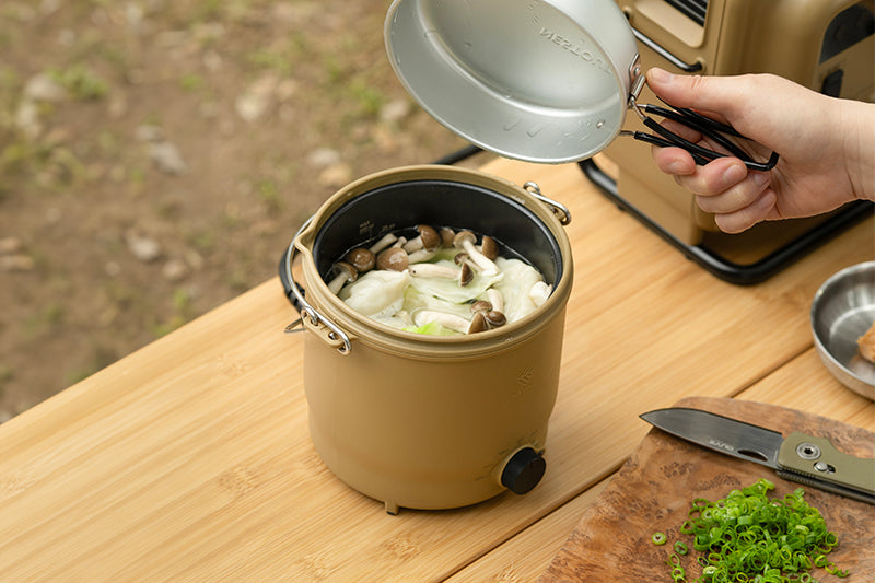 Beige cooker with cooked soup in it on top of a table