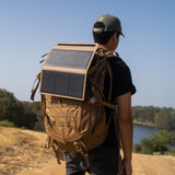 Person with a backpack featuring an attached beige solar panel on a scenic background
