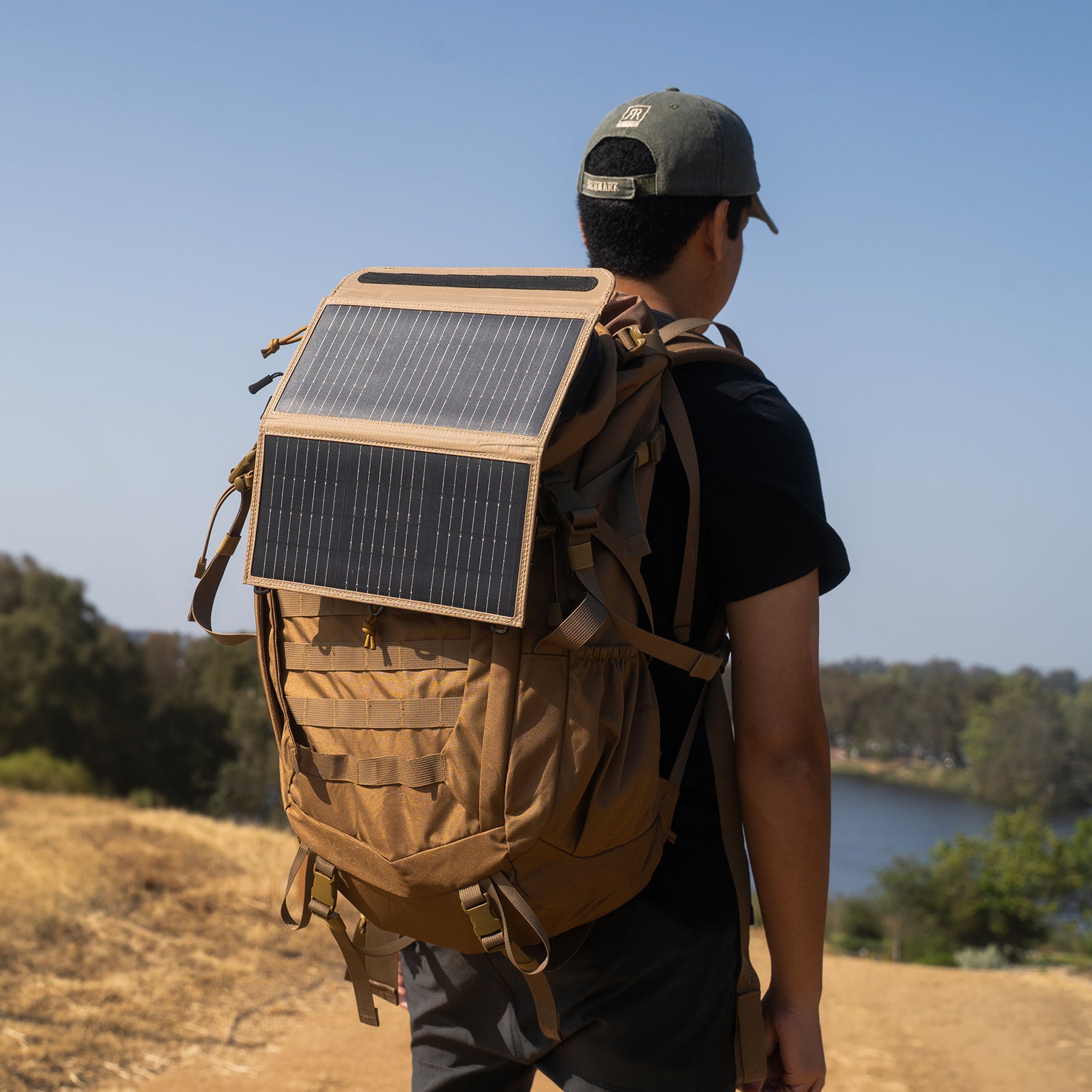 Person with a backpack featuring an attached beige solar panel on a scenic background
