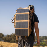 Person with a backpack featuring solar panels attached outdoors