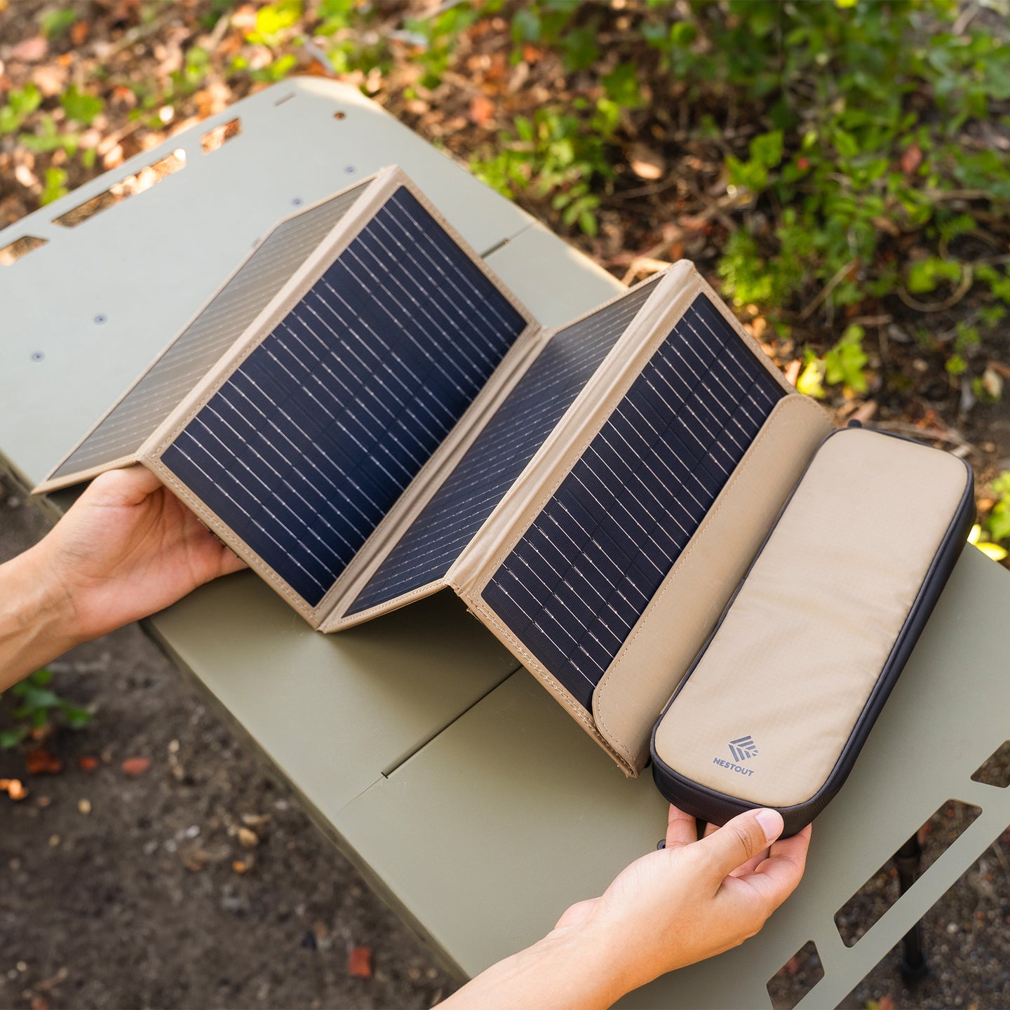Solar panel being held by a person outdoors with greenery in the background