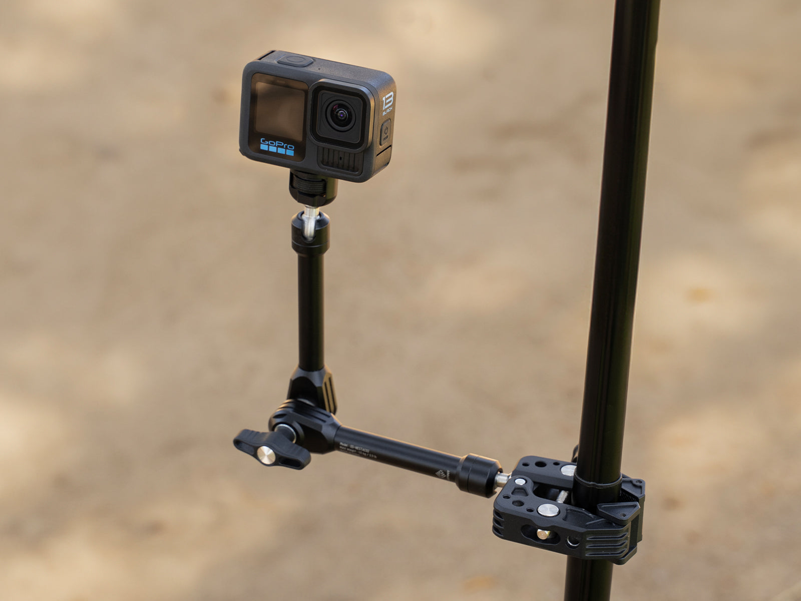 black arm clamp with a gopro attached to it while clamped onto a black pole outdoors