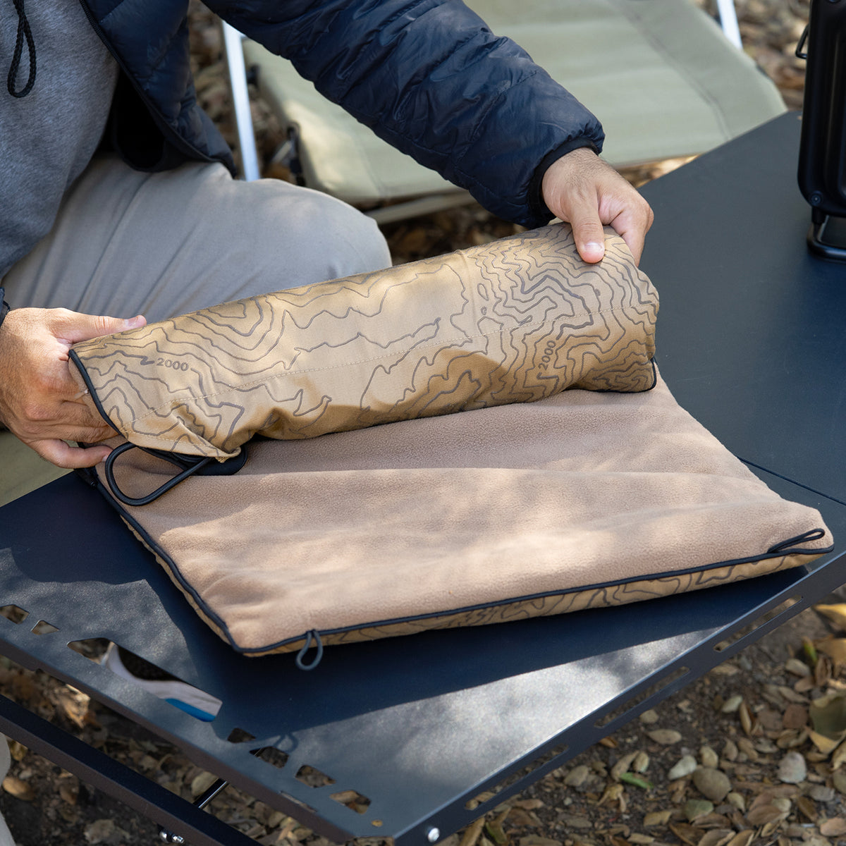Beige pad-1 heater banket being rolled up outdoors 