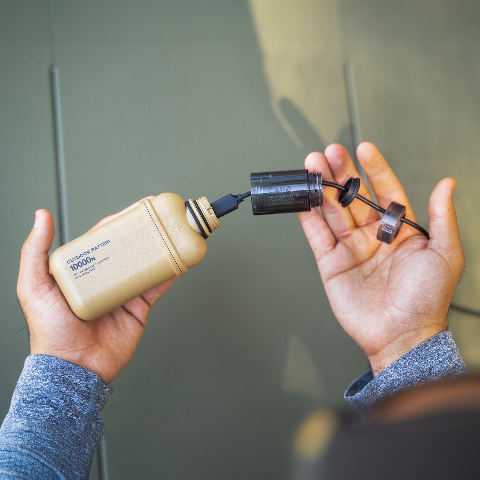 Person connecting charging cap a portable power bank to a device with a blurred background