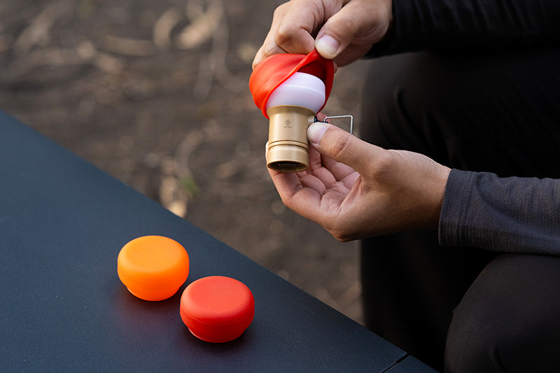 a red filter light being attached to a lamp 1 attachment and two other filters shown on a table outdoors