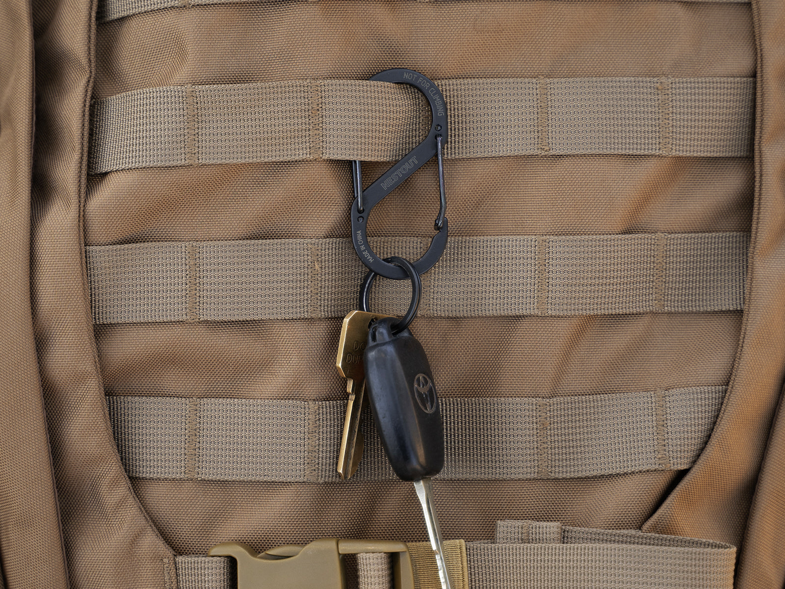 Black carabiner clipped onto a backpack with some keys attached to the carabiner