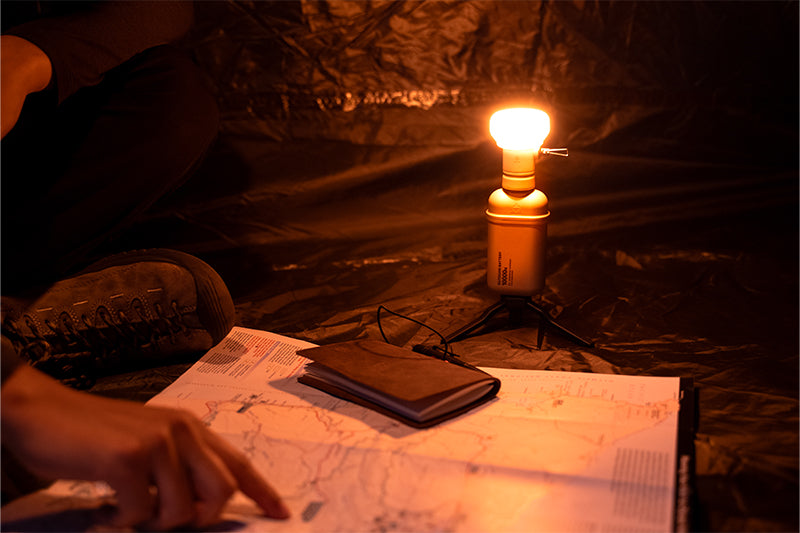 10k power bank on a tripod with a lamp attachment that has a orange filter on it in a tent