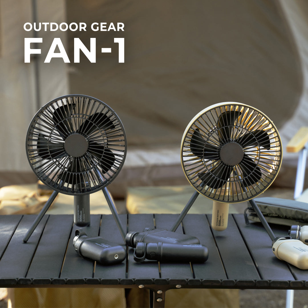outdoor gear fan-1 by nestout - features a black fan and a beige fan with matching batteries on a black table with more nestout batteries scattered across the table 