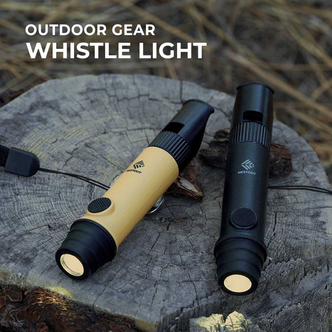 outdoor gear whistle light - features 2 NESTOUT whistle lights, one beige and black, one black on a sawed off stump outside at dusk