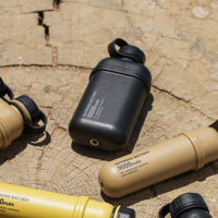 Image of nestout 10k black 5k beige colored cylinder battery packs resting on tree stump | features military IP67 rating | stores up to 10000N of power | rugged waterproof design | compact size | versatile charging | to be used with NESTOUT solar panels, fans, lamps, and flashes