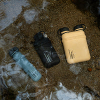 Image of nestout 10k black 15k beige 5k grey colored cylinder battery packs submerged in shallow water | features military IP67 rating | stores up to 10000N of power | rugged waterproof design | compact size | versatile charging | to be used with NESTOUT solar panels, fans, lamps, and flashes