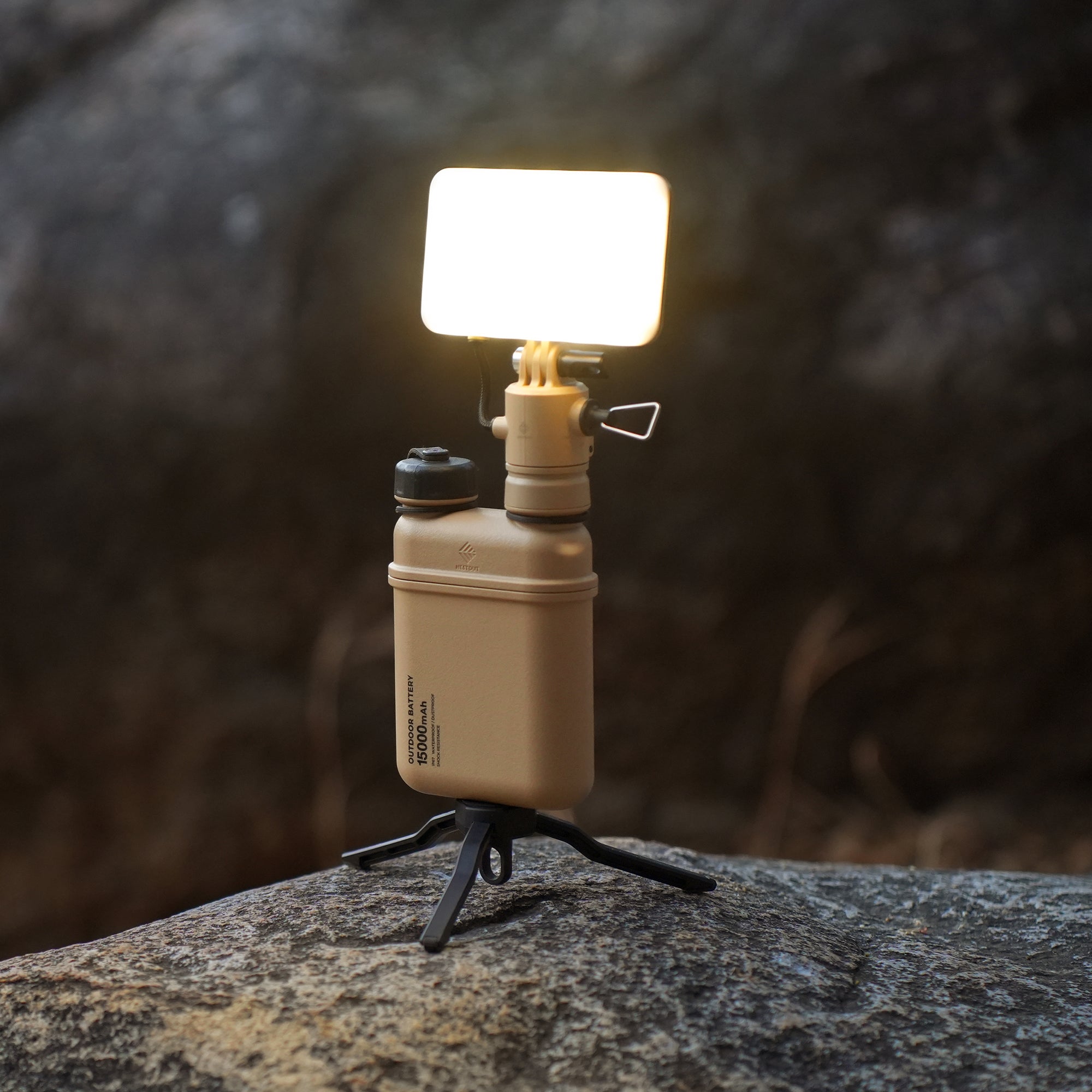 Beige 15000mAh power bank attached to the NESTOUT light accessory, standing on a rock