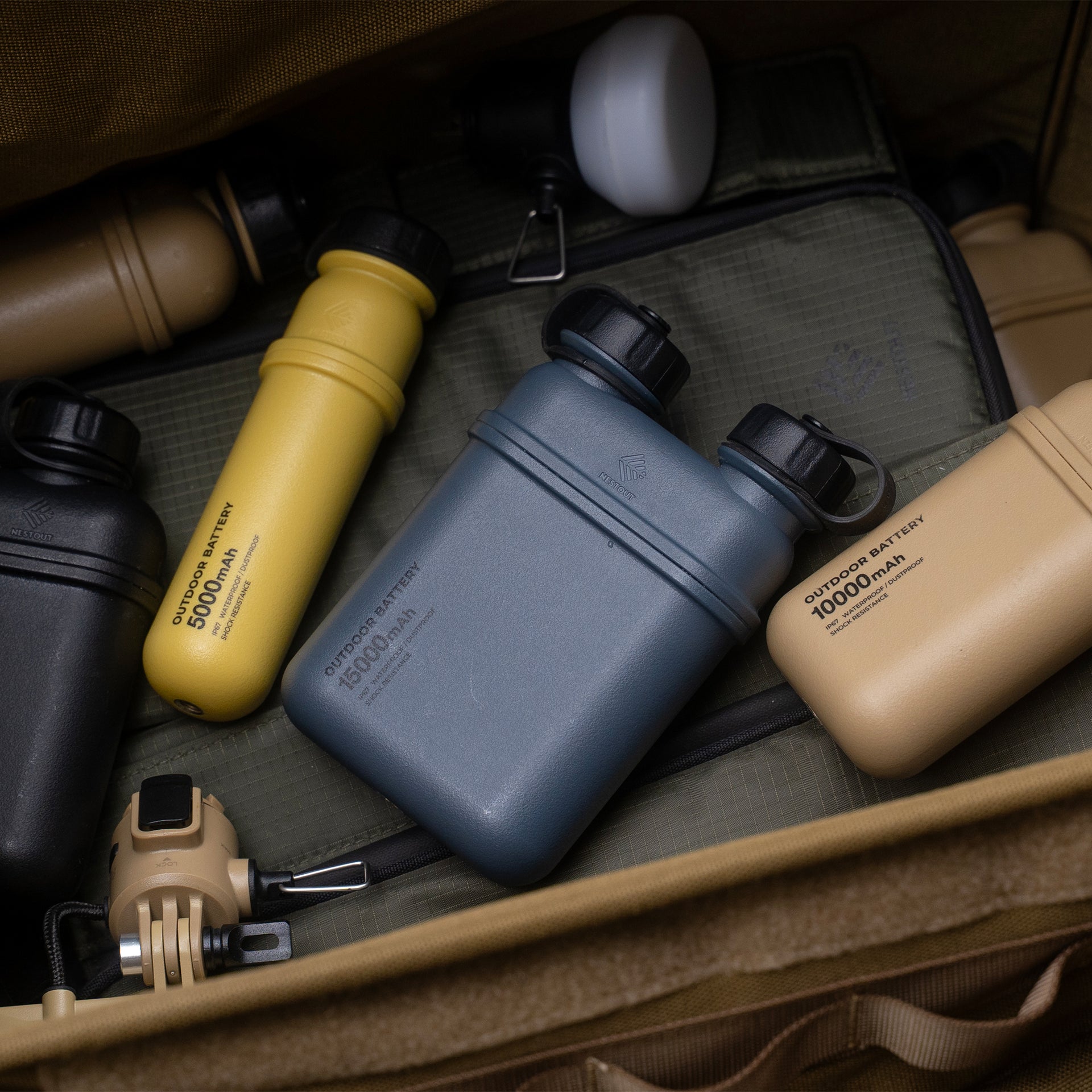 Image of nestout 15k grey cylinder battery pack with other nestout battery sizes and colros inside a storage case | features military IP67 rating | stores up to 15000N of power | rugged waterproof design | compact size | versatile charging | to be used with NESTOUT solar panels, fans, lamps, and flashes