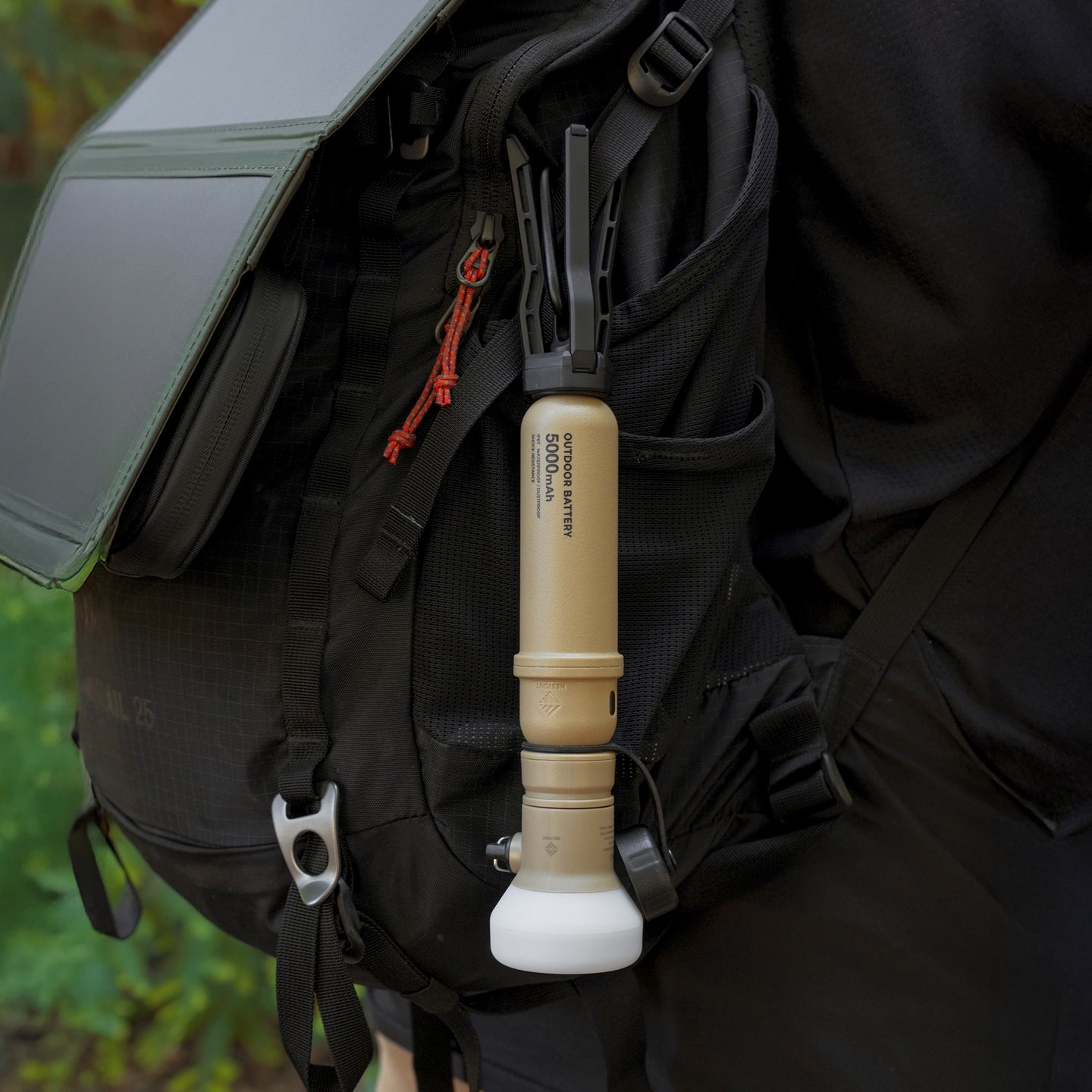 image of nestout beige colored cylinder battery pack hanging upside down on a backpack | features military IP67 rating | stores up to 5000N of power | rugged waterproof design | compact size | versatile charging | to be used with NESTOUT solar panels, fans, lamps, and flashes