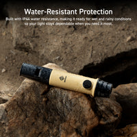 beige and black whistle light with water droplets all over, sitting on a brown rock | Overlay text reads: water-resistant protection: built with IP44 water resistance, making it ready for wet and rainy conditions so your light stays dependable when you need it most. 